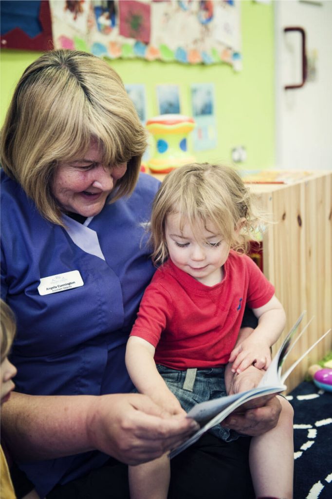 Bright swans day staff helps child read a book